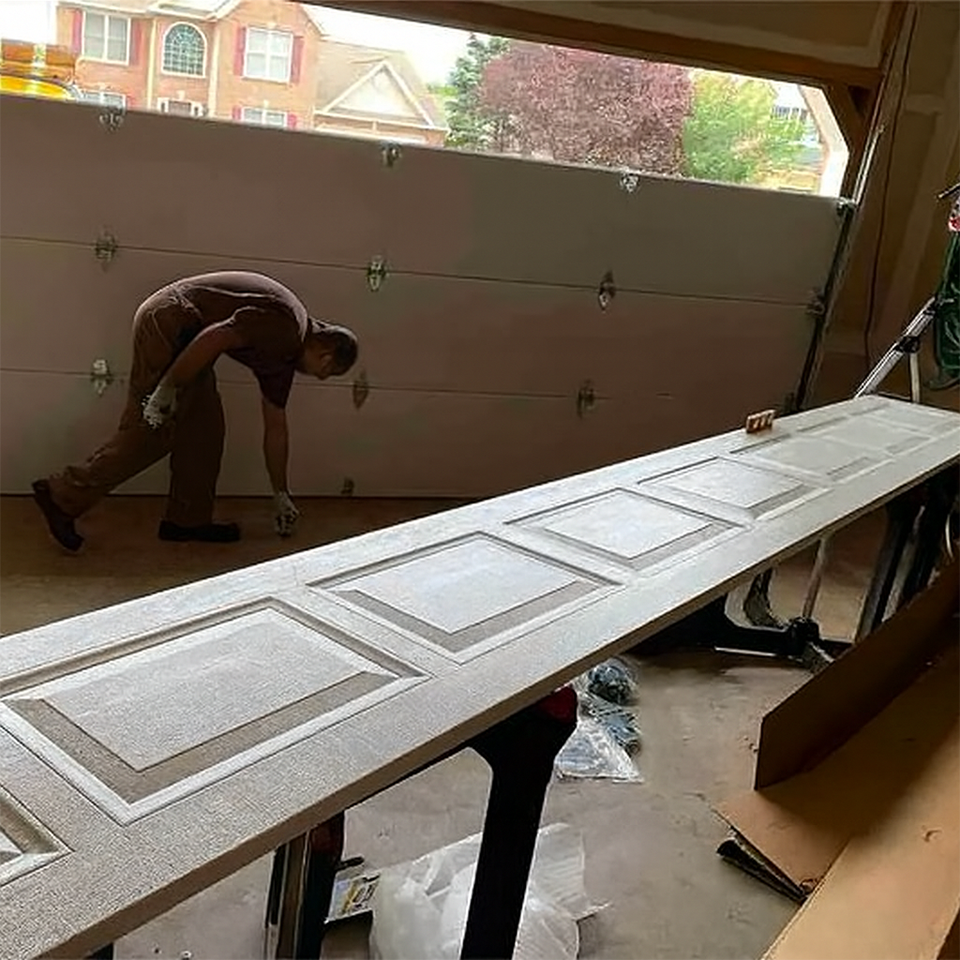 Technician installing a new garage door panel inside a residential garage